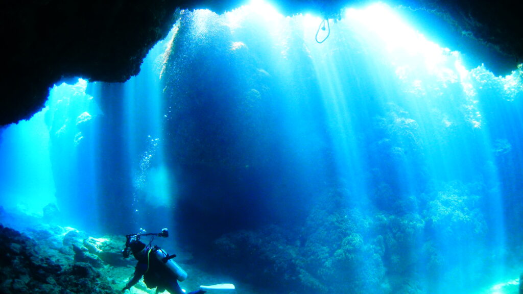 光が指す洞窟で写真を撮るダイバー